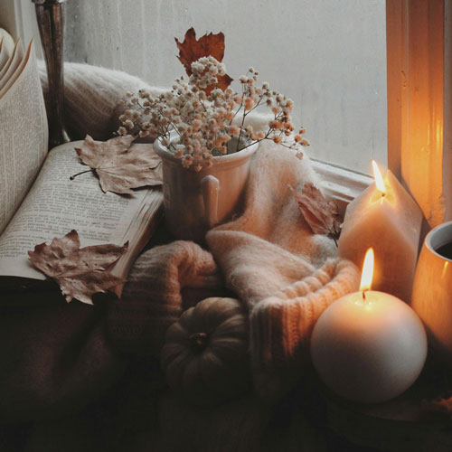 candles, pumpkins and a book on a rainy day