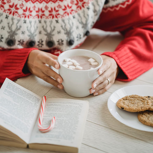 woman drinking hot chocolate and reading a book